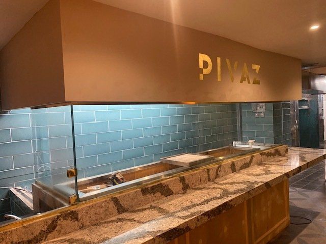Pink glass splashbacks in domestic kitchen, white cupboards surrounding