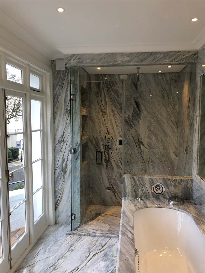 glass shower curtain with marble effect wall behind