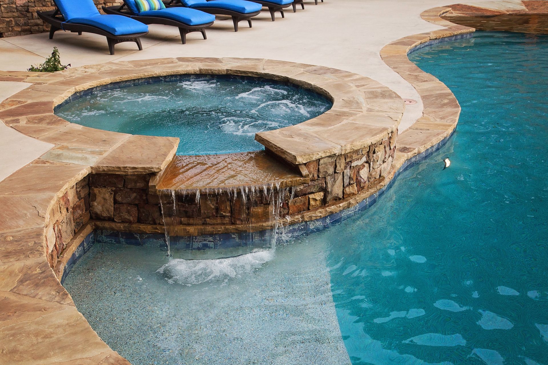 A large swimming pool with a hot tub in the middle of it
