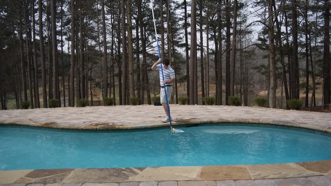 A man is standing on the edge of a swimming pool.