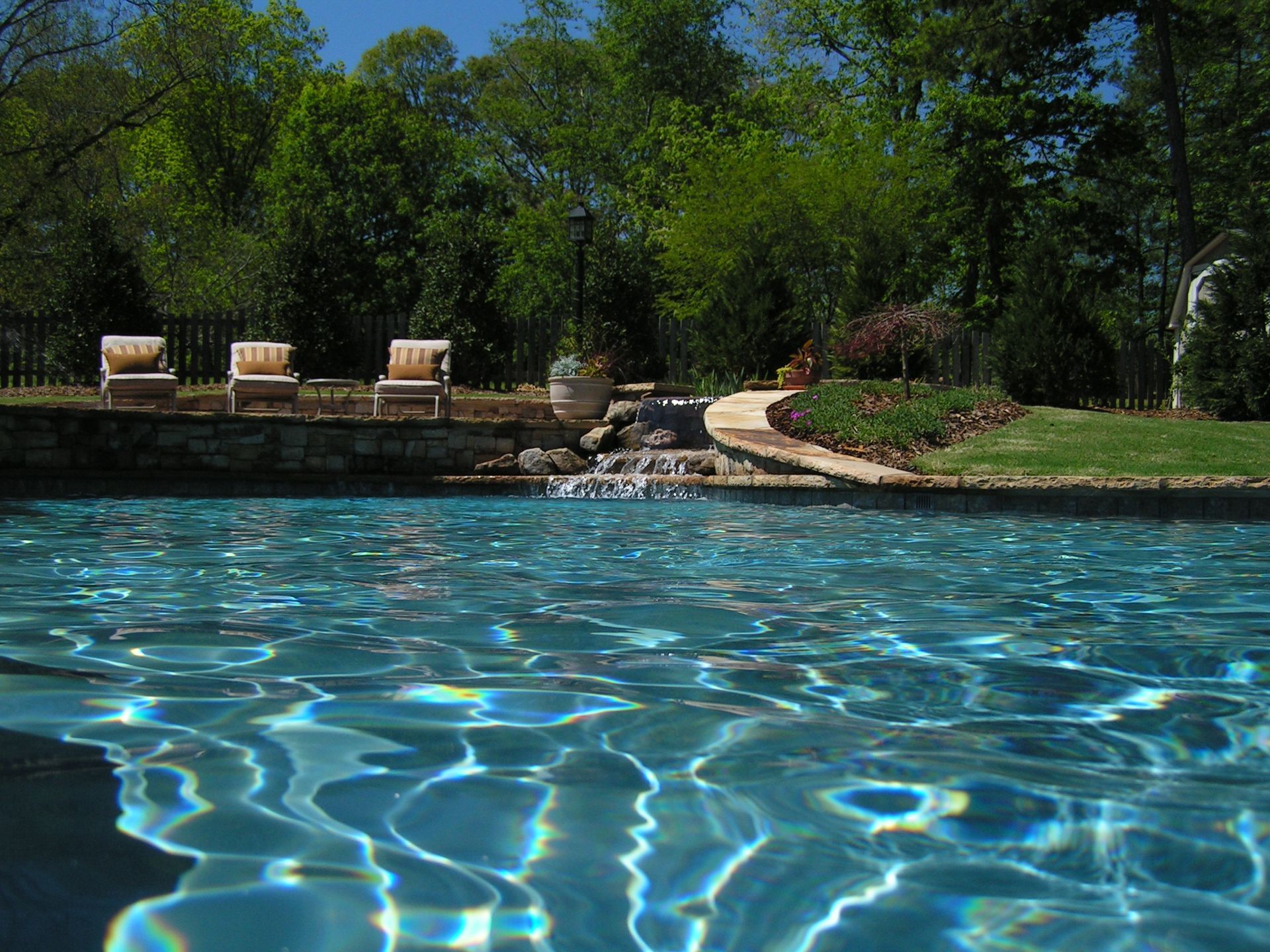 A large swimming pool with chairs and trees in the background