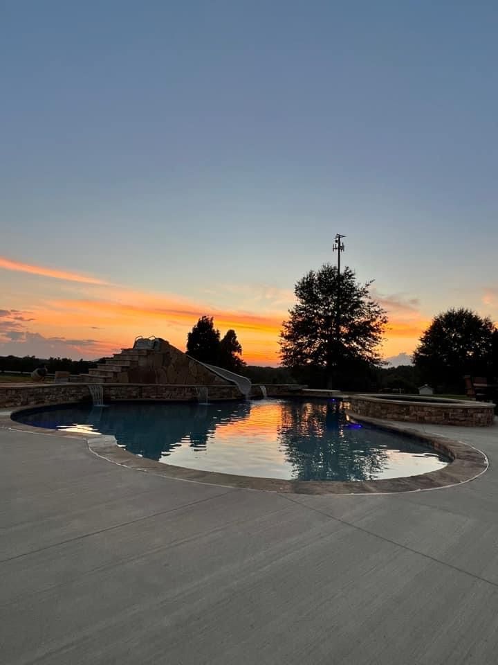 A large swimming pool with a sunset in the background.