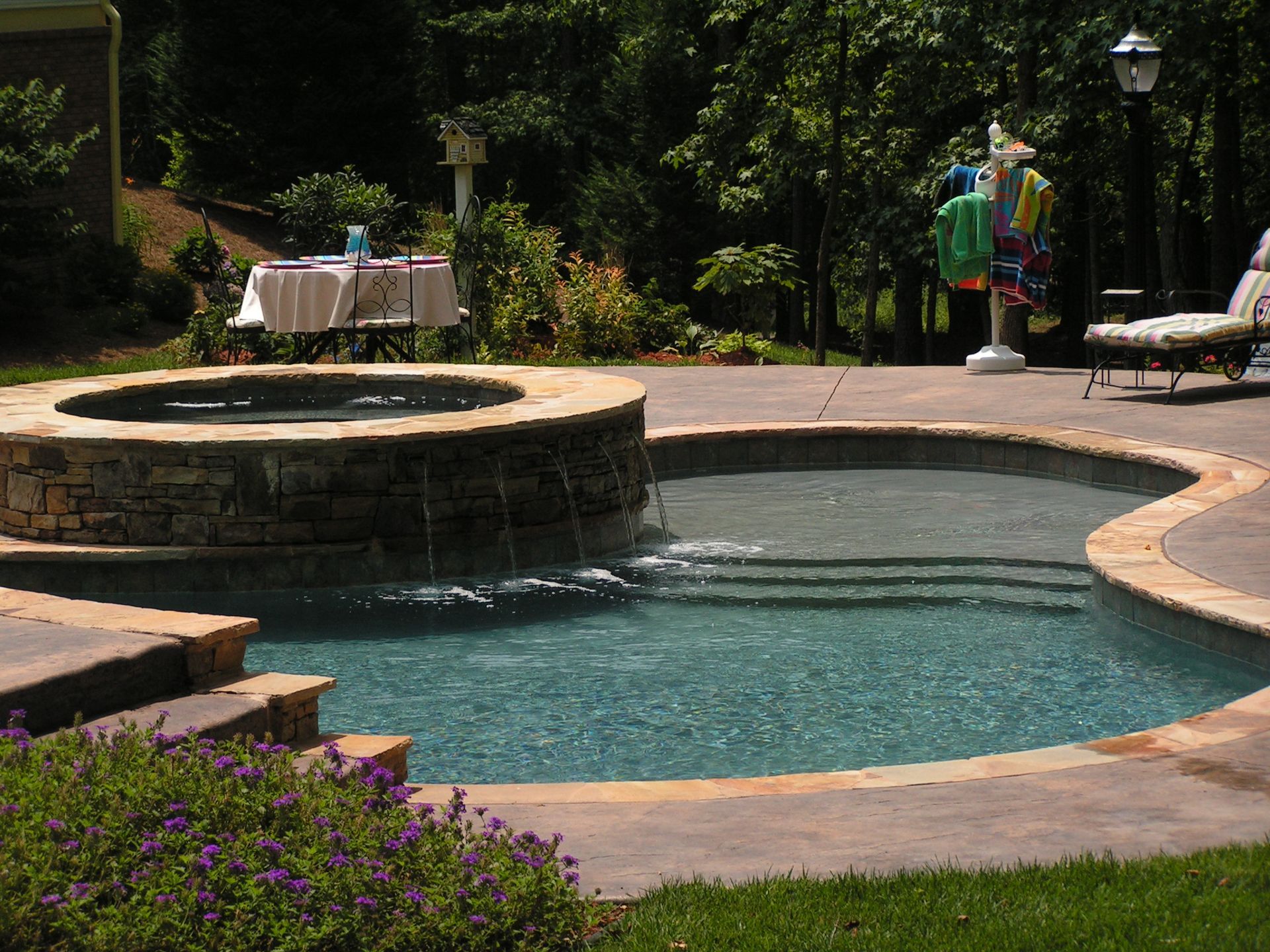 A swimming pool with a table and chairs in the background