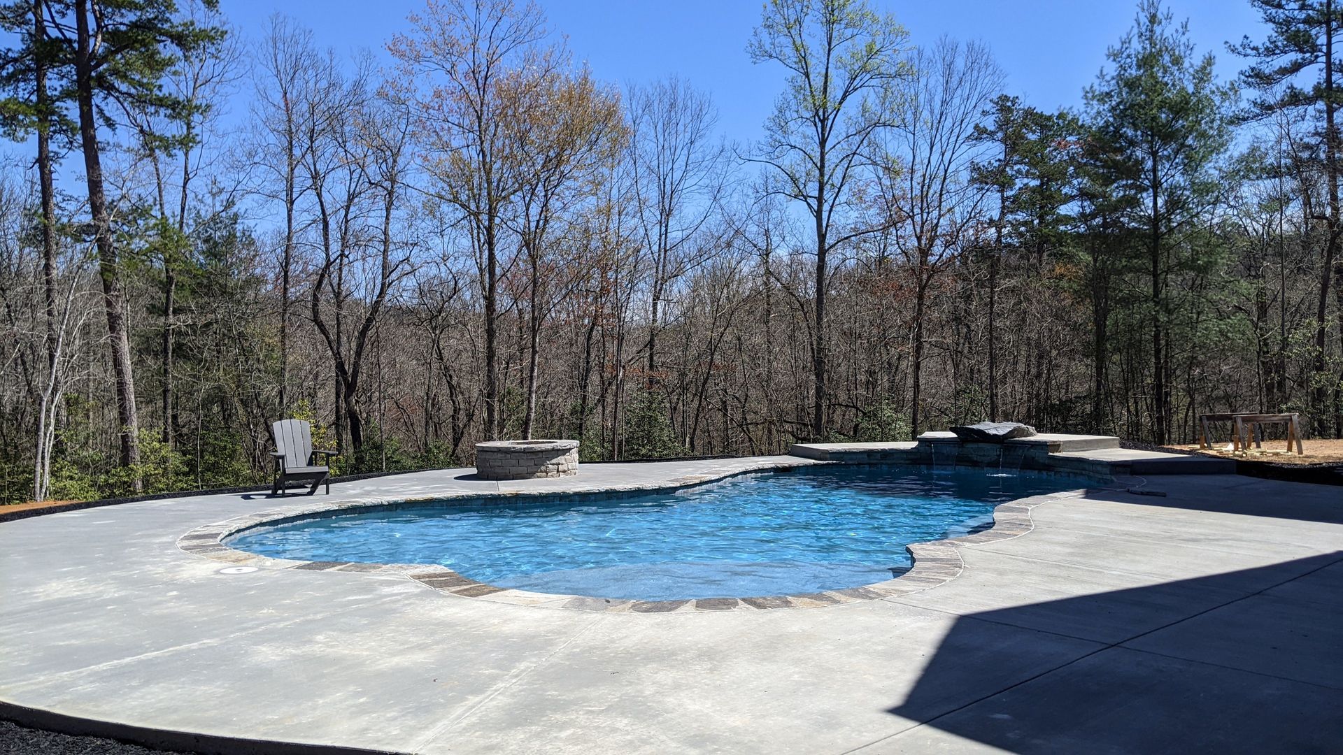 A large swimming pool is surrounded by trees on a sunny day.