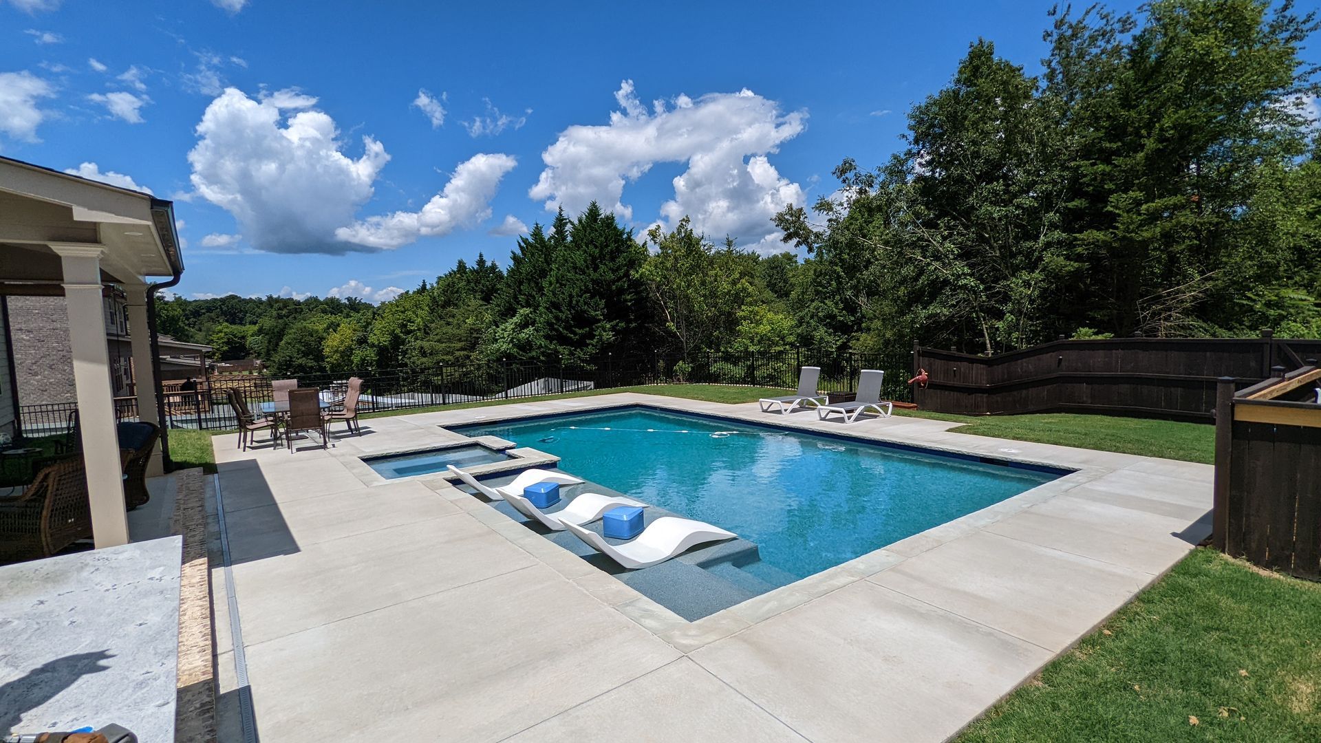There is a large swimming pool in the backyard of a house.