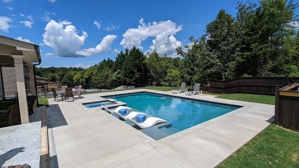 There is a large swimming pool in the backyard of a house.