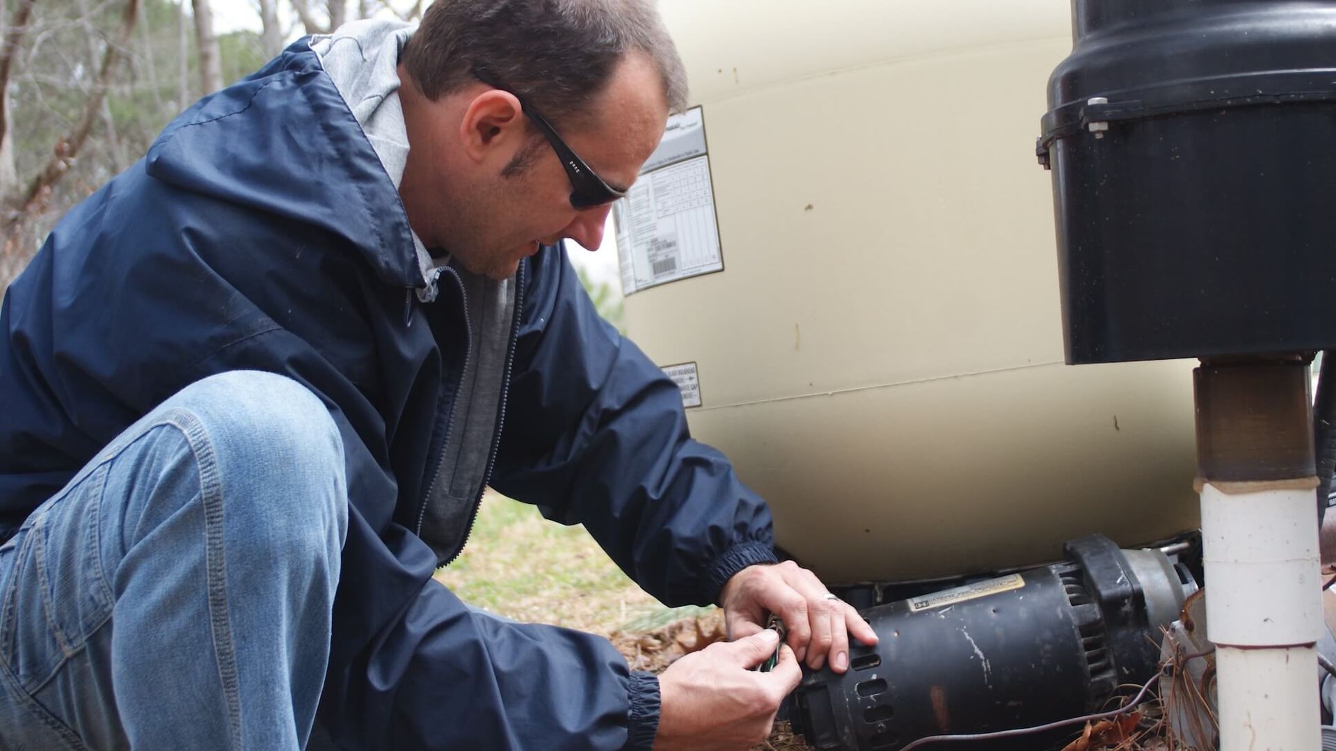 A man wearing sunglasses is working on a pipe