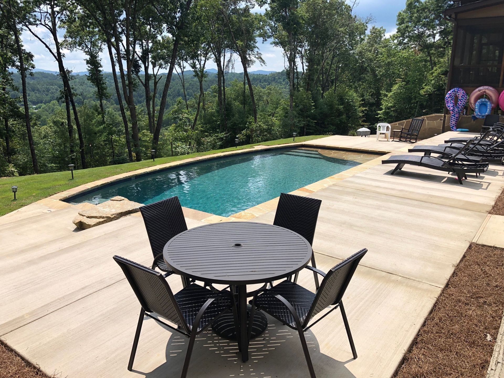 A table and chairs are sitting next to a large swimming pool.