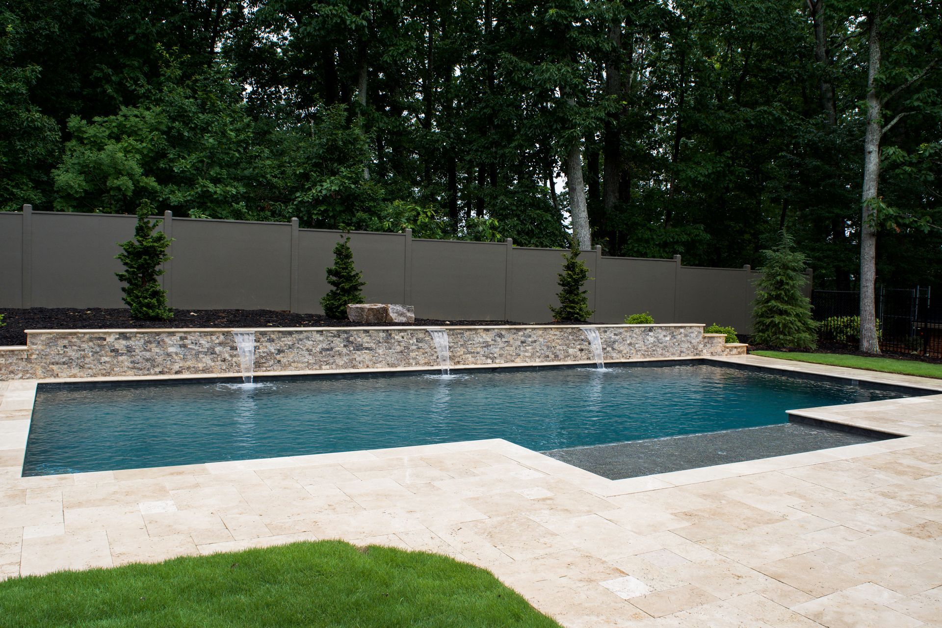 A large swimming pool with a waterfall in the backyard.