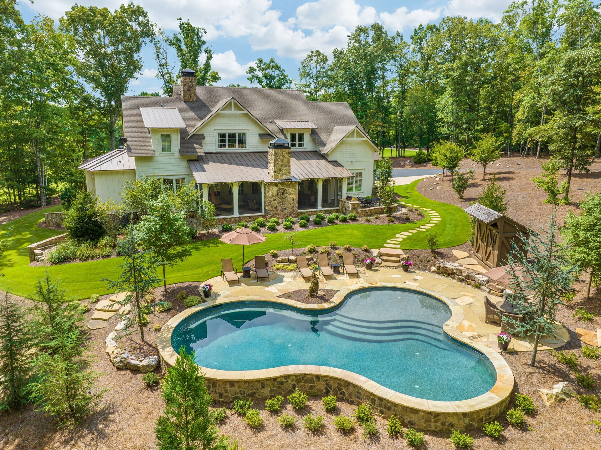 An aerial view of a large house with a large swimming pool in front of it.