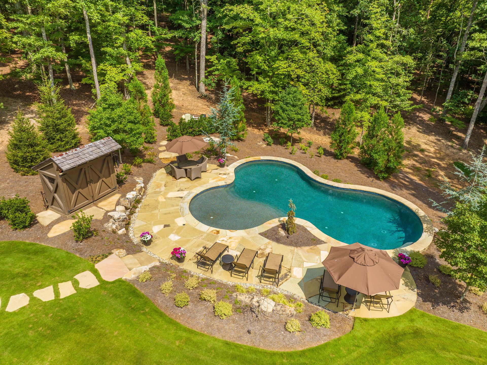 An aerial view of a large swimming pool surrounded by trees.
