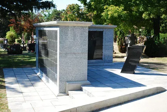 Outdoor granite memorial with engraved panels on a paved plaza in a park