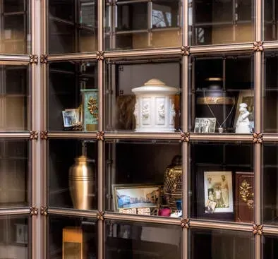 Decorative wall shelf with gold and white vases, framed photos, and ornaments in square cubbies