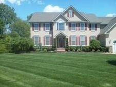 A large brick house with a lush green lawn in front of it.