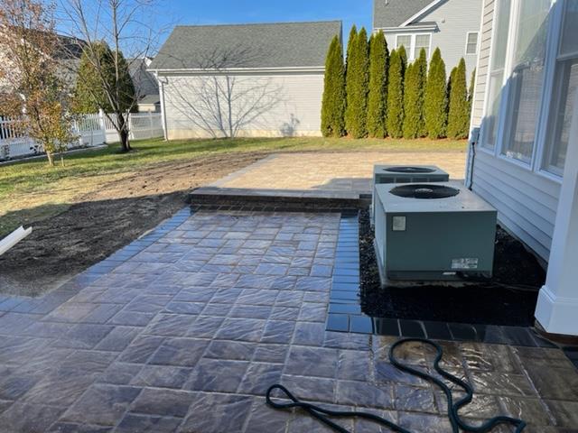 A patio with two air conditioners on it and a house in the background.