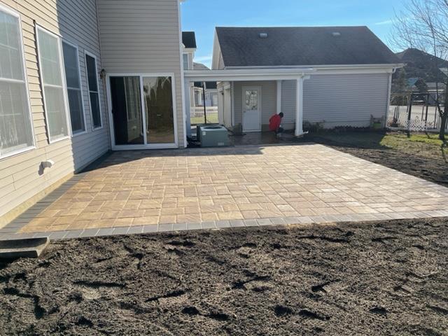 A patio is being built in the backyard of a house.