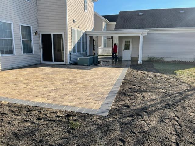 A man is standing in front of a house with a patio in front of it.