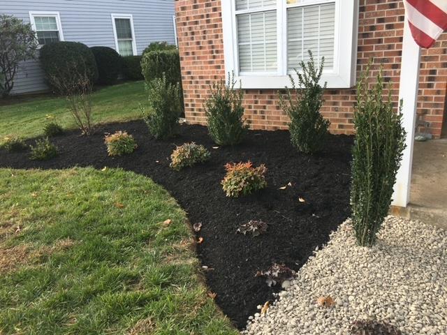 A brick house with a lush green lawn and a flag in front of it.