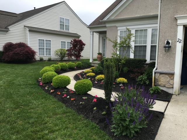 A house with a lush green lawn and a walkway in front of it.
