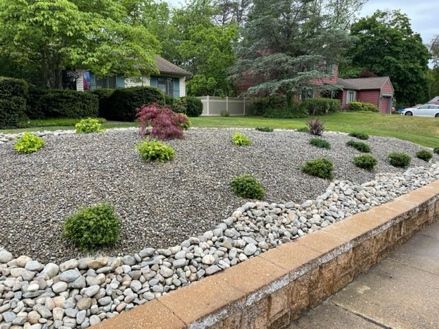 A garden with rocks and plants in front of a house.