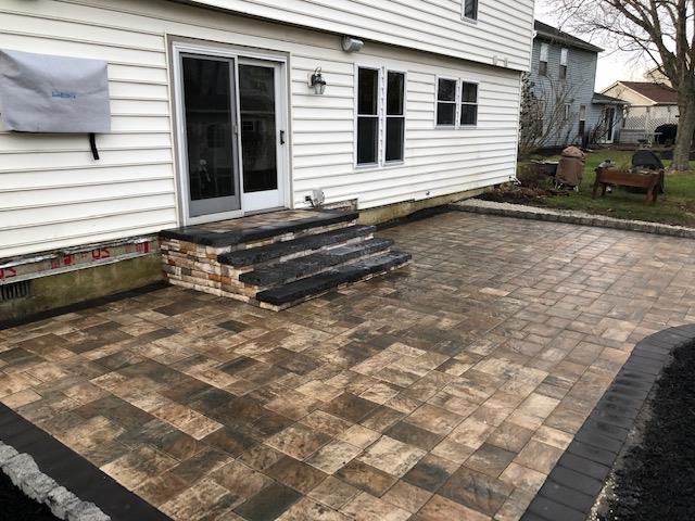 A patio with stairs leading to the back of a house.