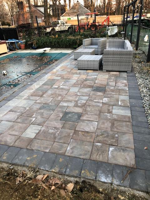 A patio with a couch and chairs next to a pool.