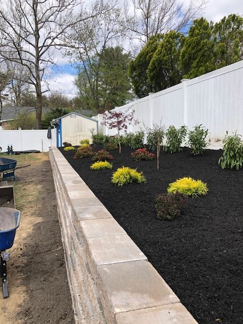 A garden with a white fence and a brick wall