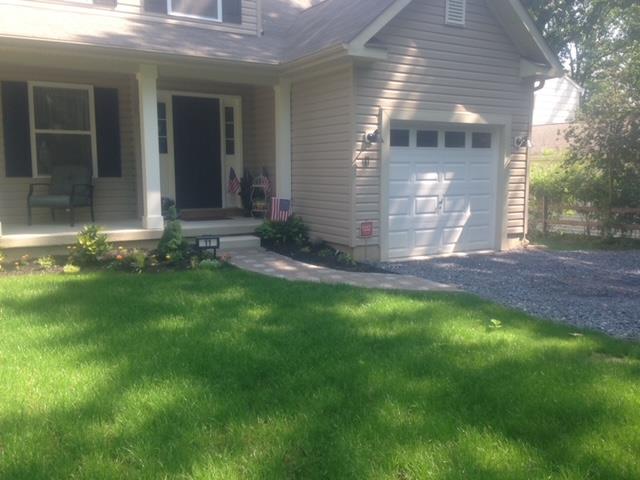A house with a white garage door and a large lawn in front of it.