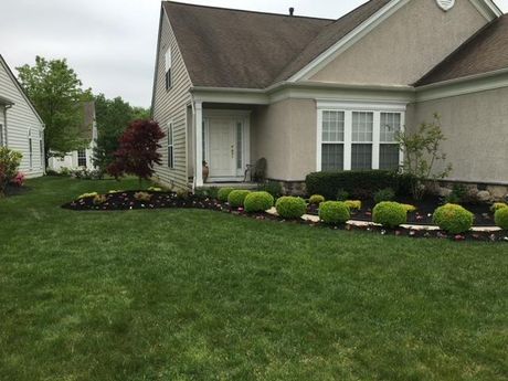 A house with a lush green lawn and bushes in front of it.