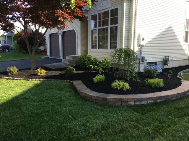 A house with a lush green lawn and a garden in front of it.