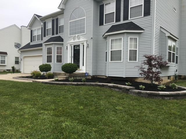A large white house with black shutters and a large lawn in front of it.