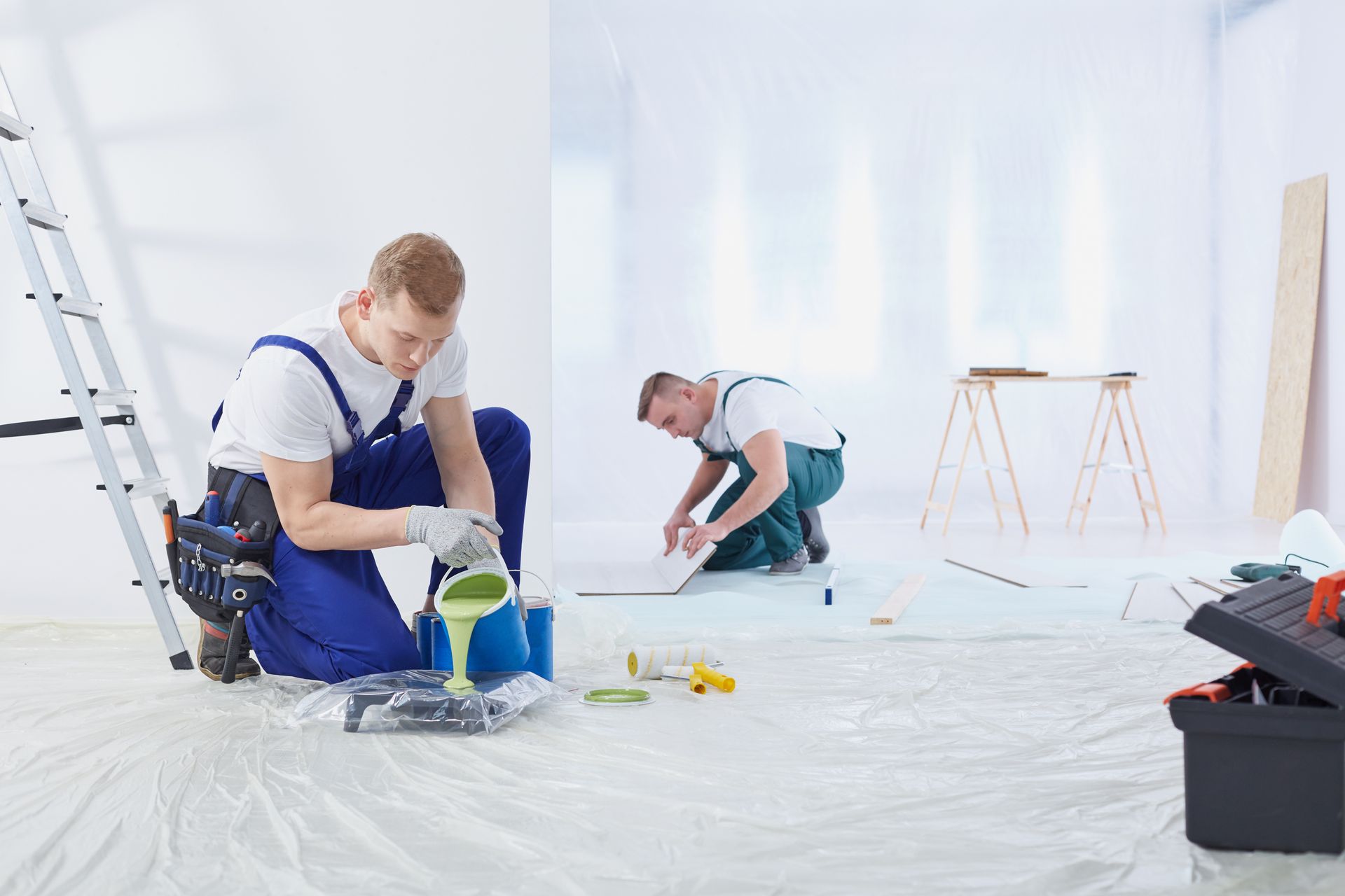 Two painters are preparing to paint a home interior with white walls.