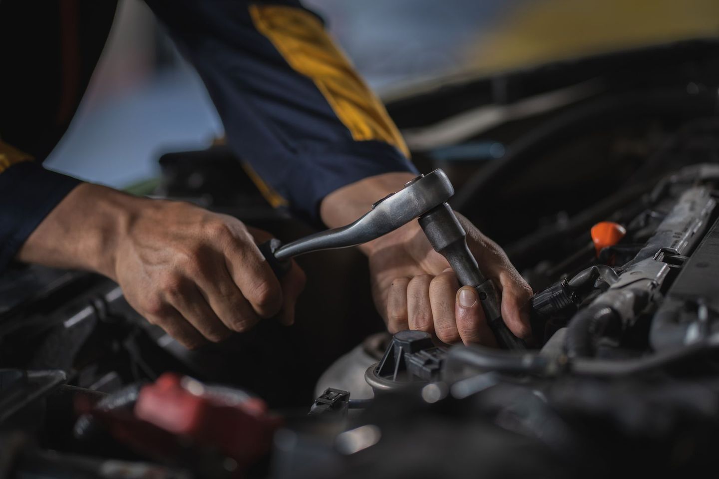 Mechanic using a wrench to work on a car engine in a garage. Mechanic using a wrench to work on a car engine in a garage.