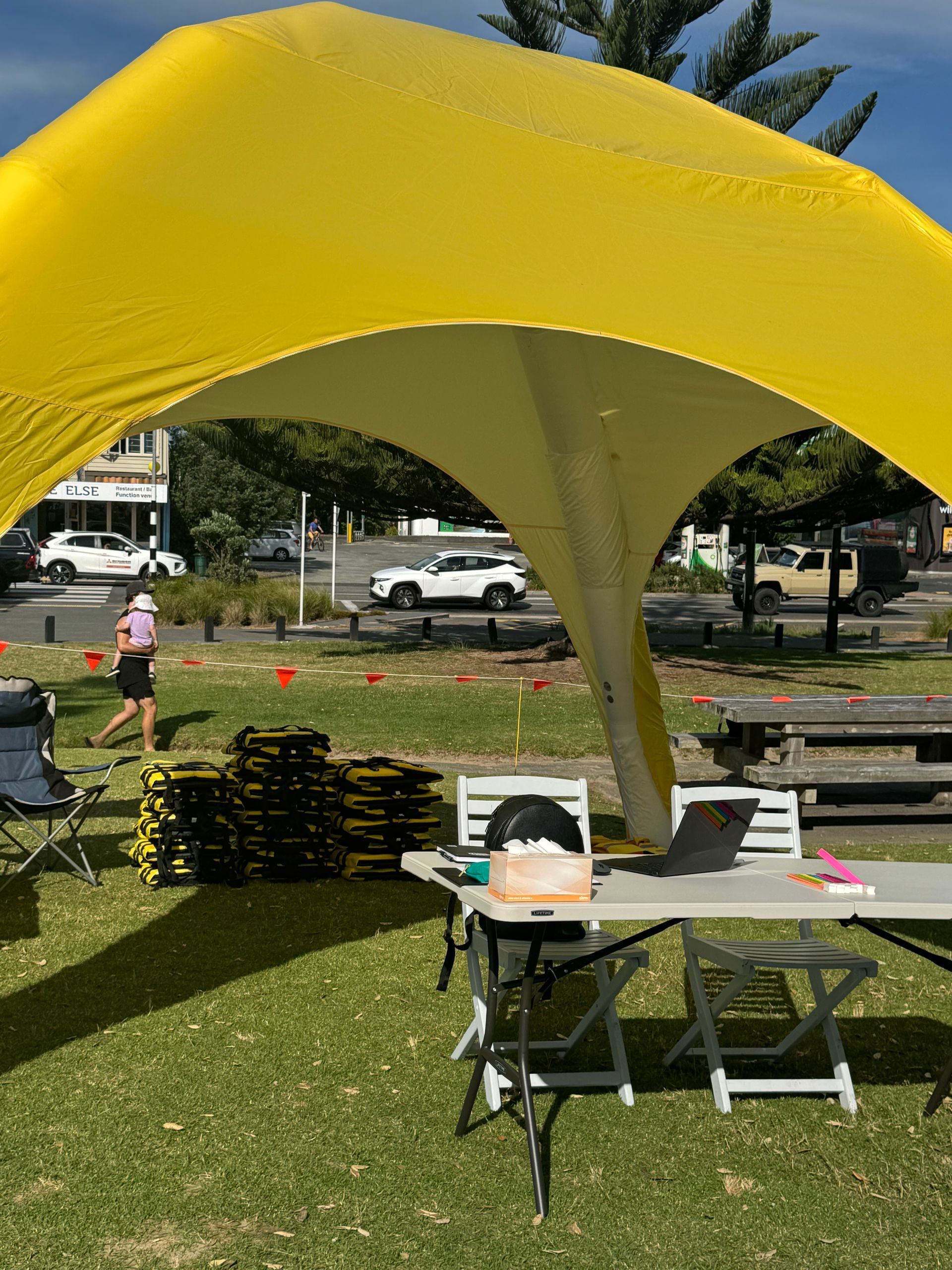 Yellow canopy over a table set up outdoors. A runner passes by.