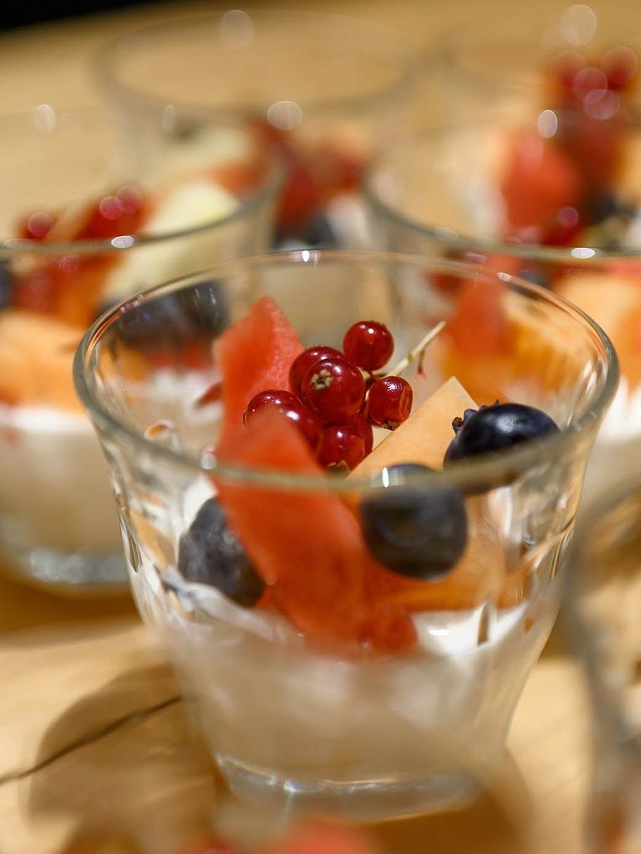 Een close-up van een glas gevuld met fruit en yoghurt op een tafel.