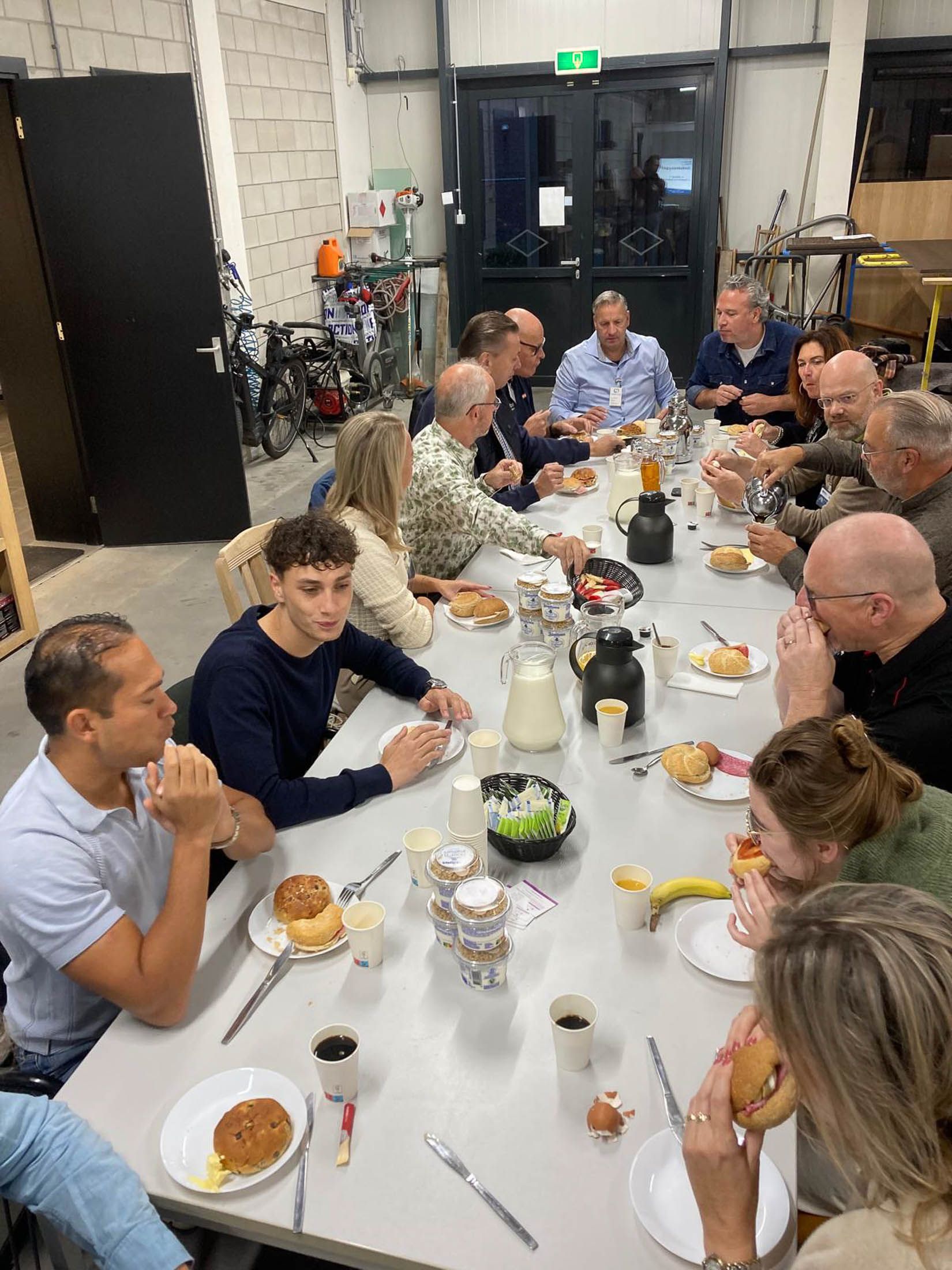 Een groep mensen zit aan een lange tafel te eten.