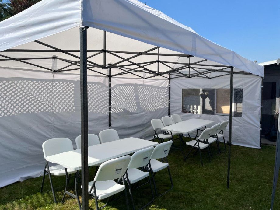 A white tent with tables and chairs inside of it.