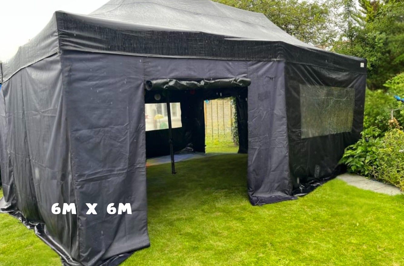 A black tent is sitting on top of a lush green field.