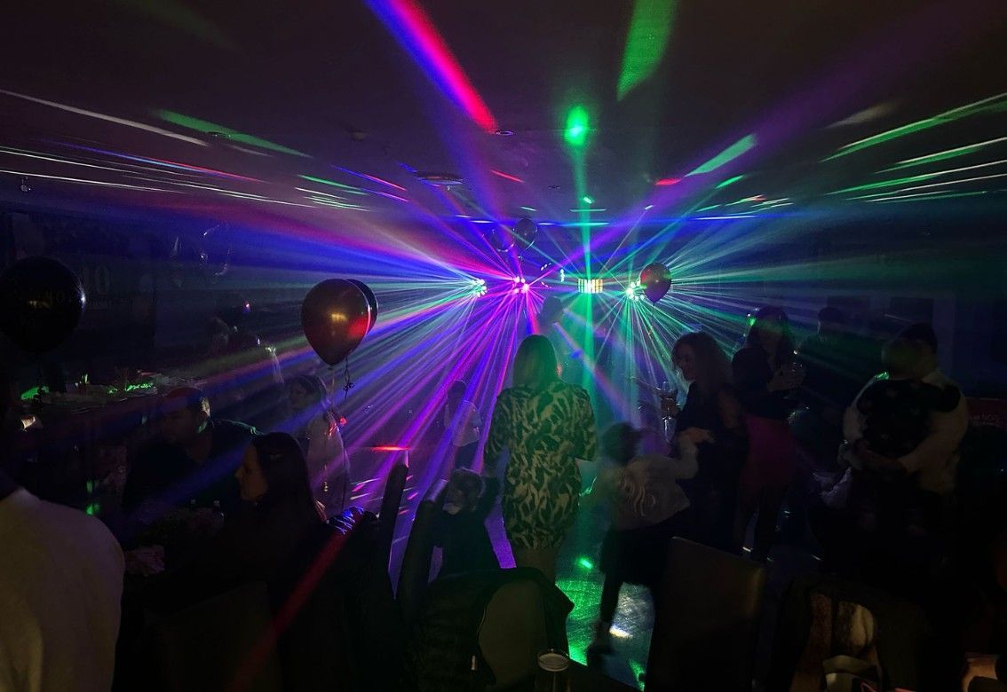 A group of people are dancing at a party in a dark room.