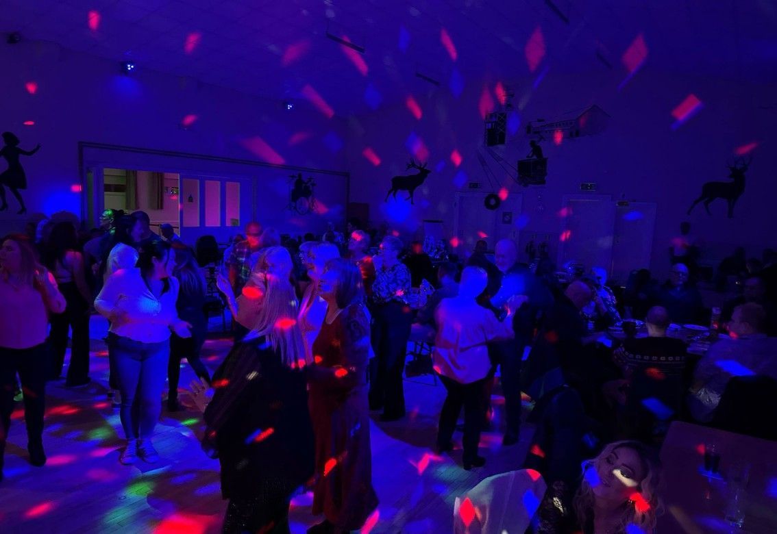 A group of people are dancing in a dark room with disco lights