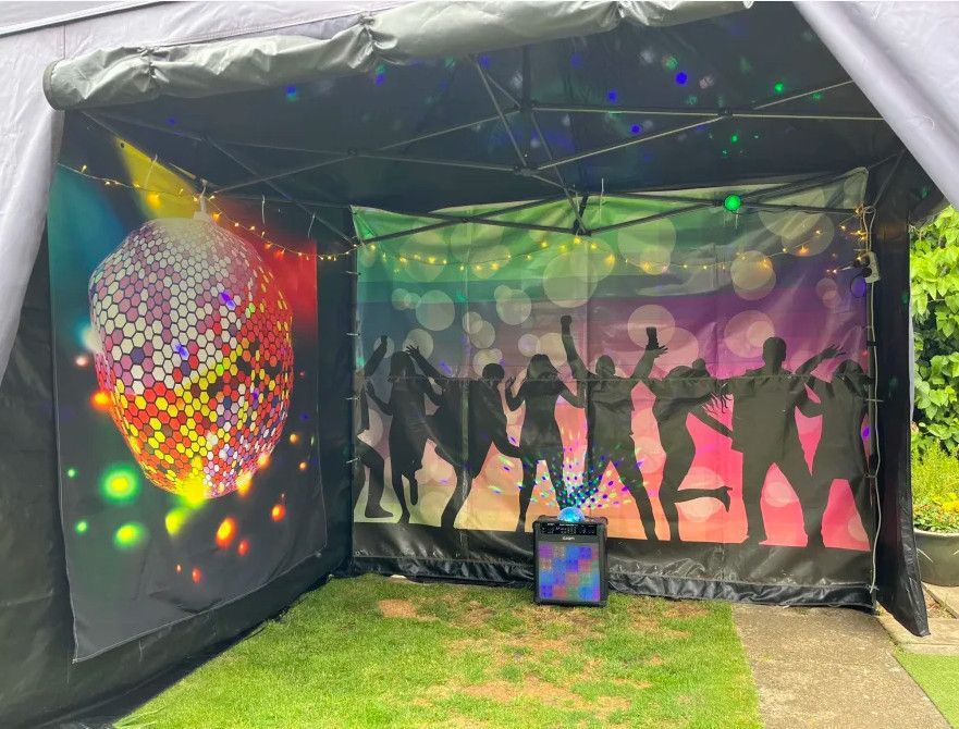 A tent with a disco ball and silhouettes of people dancing on it.
