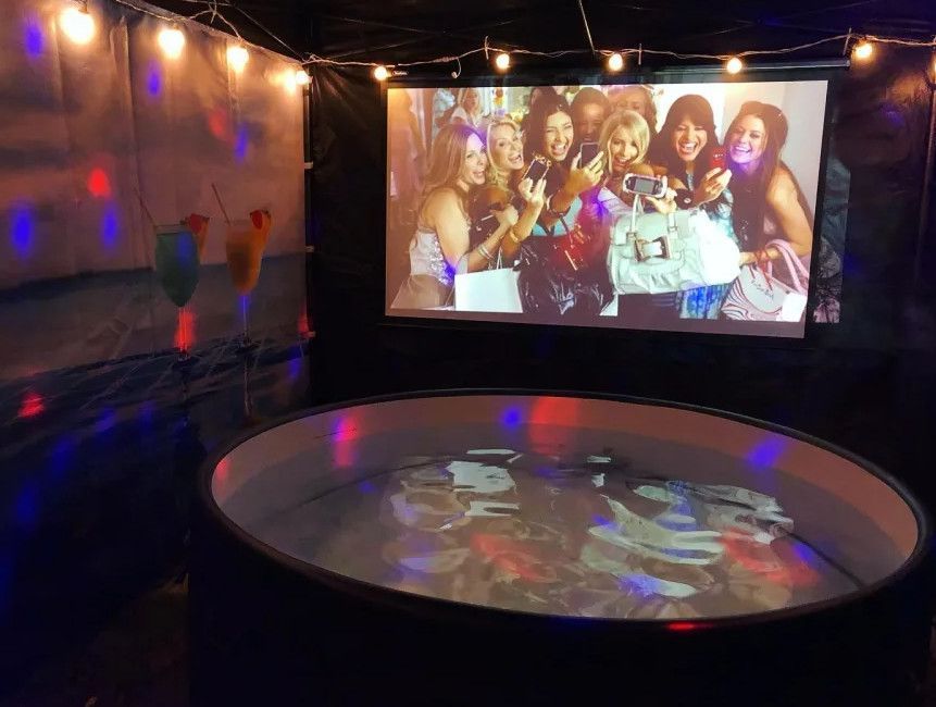 A group of women are posing for a picture in front of a large screen.