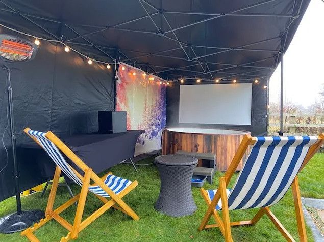 There are lawn chairs and a projector screen under a tent.