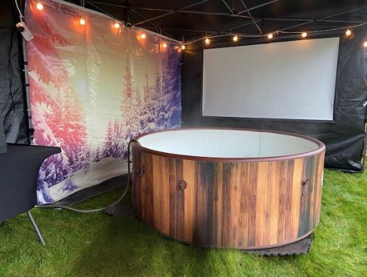 A wooden hot tub is sitting in front of a projector screen.