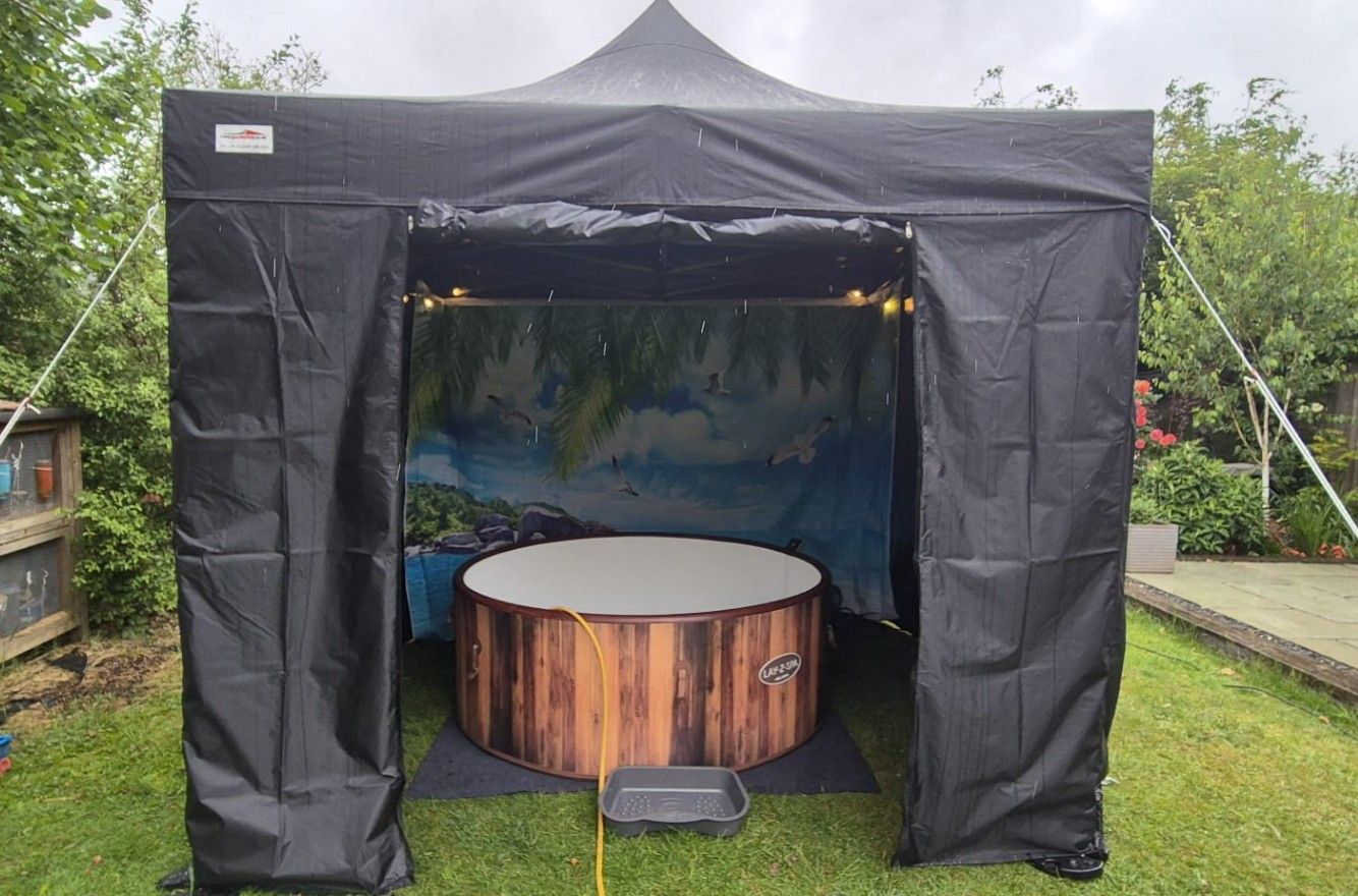 A wooden hot tub with steps in a backyard with a palm tree in the background.