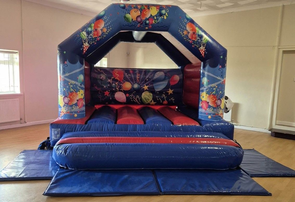 A blue and red bouncy castle is sitting on a blue mat in a room.
