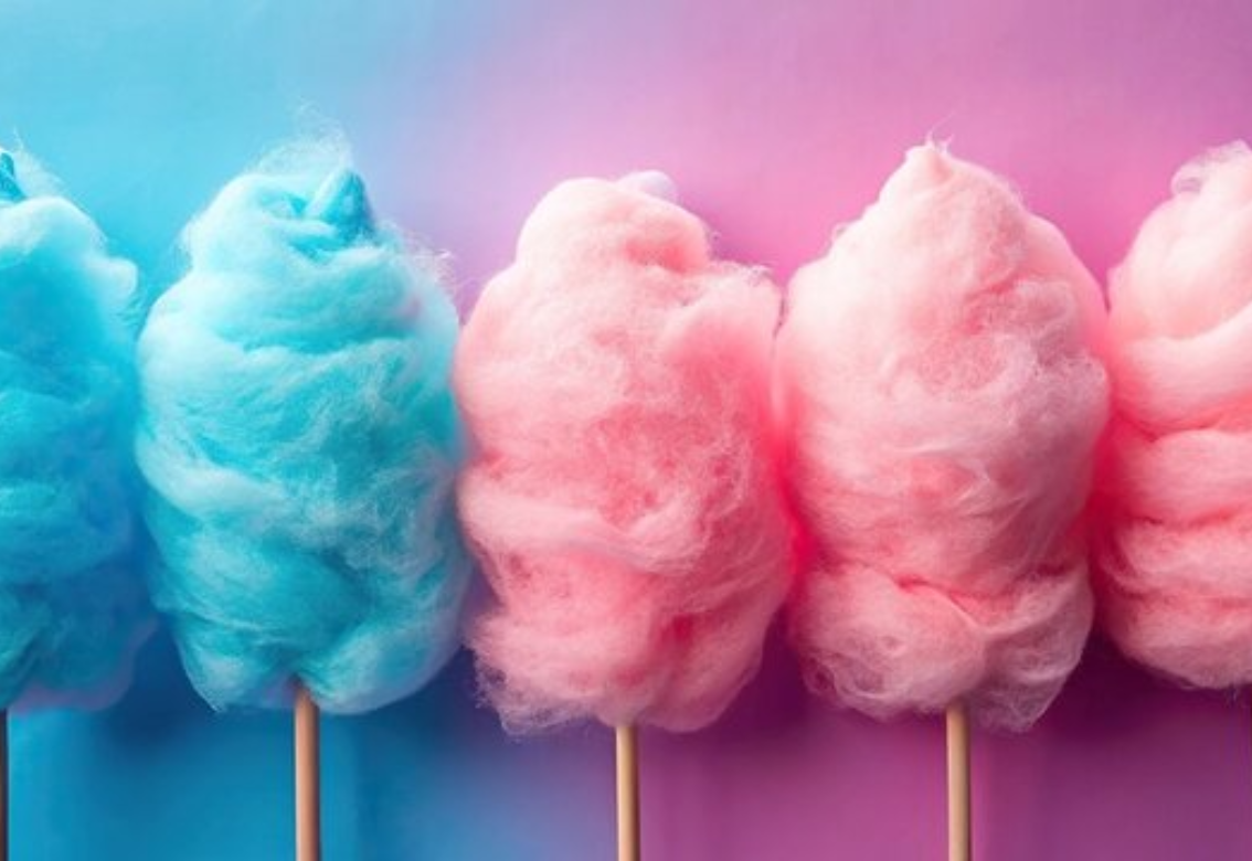 A person is making cotton candy in a pink cotton candy machine.
