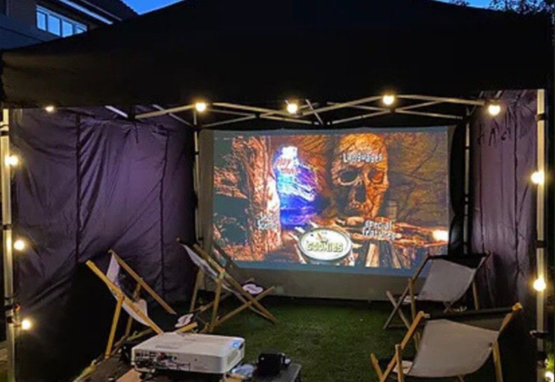 A projector is sitting on a table in front of a large screen.
