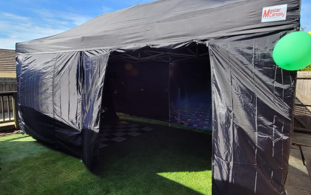 A black tent is sitting on top of a lush green field.
