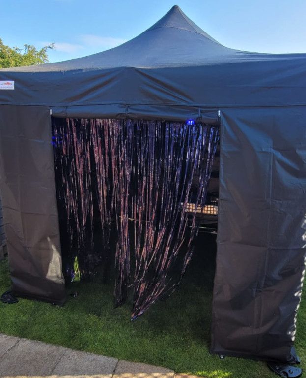 A black tent with purple tinsel hanging from it